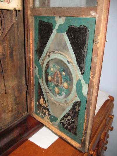 The inside of the door. A mouse lived in the clock for a while, note the door below the painted glass.